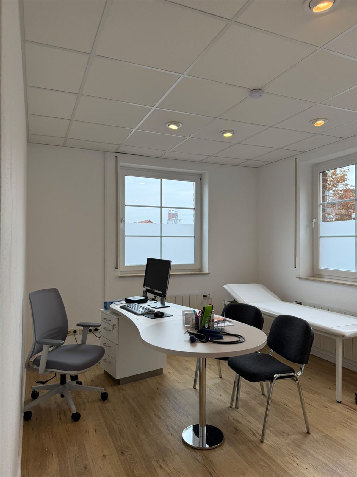 Sprechzimmer mit Schreibtisch, Stühlen und Untersuchungsliege